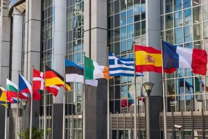 Een rij Europese vlaggen, wapperend voor het gebouw van het Europese Parlement
